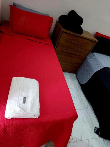 a red bed with a white towel on top of it at Cobertura duplex com Jacuzzi e vista espetacular para a praia e a cidade in Praia Grande