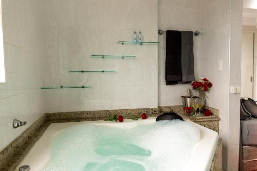 a bath tub with blue water in a bathroom at Cobertura duplex com Jacuzzi e vista espetacular para a praia e a cidade in Praia Grande