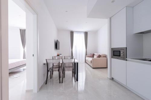 a white kitchen and dining room with a table and chairs at Alberti Apartments in Trapani