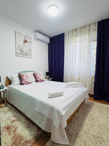 a bedroom with a large bed with blue curtains at Apartament David in Neptun