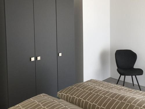 a bedroom with a bed and a black chair at Ferien- Und Winzerhof Simon in Freiburg im Breisgau