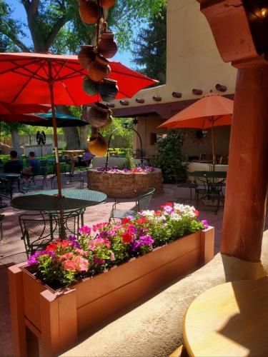 a patio with tables and chairs with flowers and umbrellas at El Pueblo Lodge in Taos