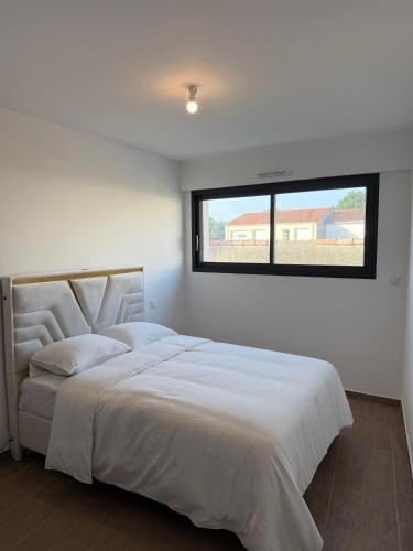 ein Schlafzimmer mit einem großen weißen Bett mit einem Fenster in der Unterkunft Maison La Pornicaise 11 in Saint-Jean-de-Monts
