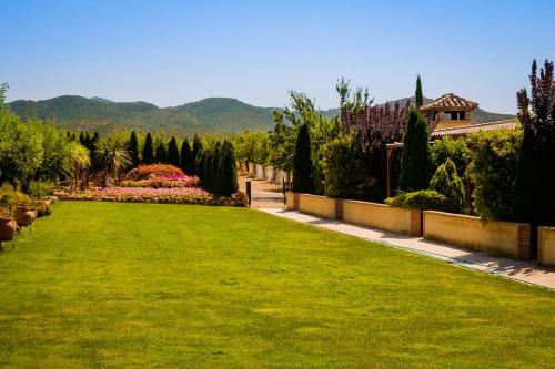 a garden with a green lawn and trees and a house at Masía Durbá Hotel in Castellnovo