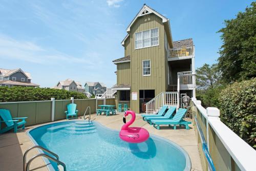 a swimming pool with a pink swan in front of a house at Lauren Lee in Nags Head
