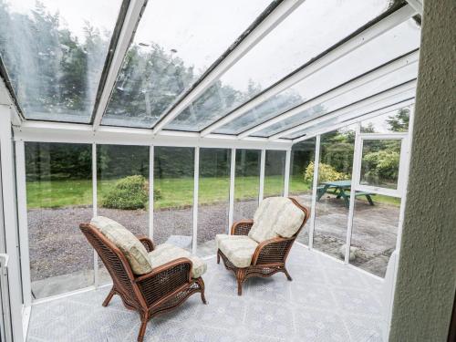 a glass conservatory with two chairs and a table at Lilly's Bungalow in Timoleague