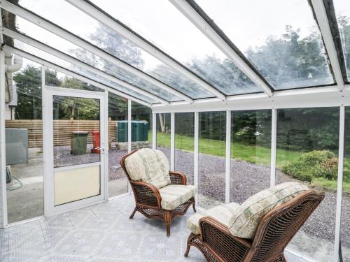a conservatory with two chairs and a glass ceiling at Lilly's Bungalow in Timoleague