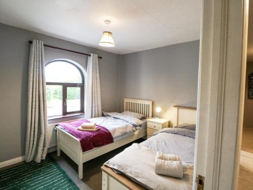 a bedroom with two beds and a window at Lilly's Bungalow in Timoleague