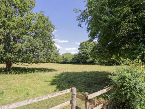 a wooden fence in a field with trees at The Old Reading Room in Stow on the Wold