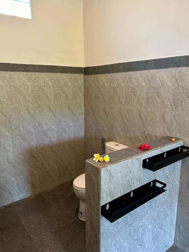Un baño con inodoro y un mostrador con flores. en Dewi Teduh Villa, en Sidemen