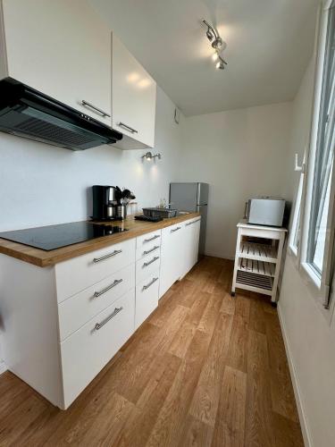 une cuisine avec des armoires blanches et un plancher en bois dans l'établissement Duplex 70m2 proche mer, 2 chambres, terrasse, parking gratuit dans la rue, à Saint-Malo