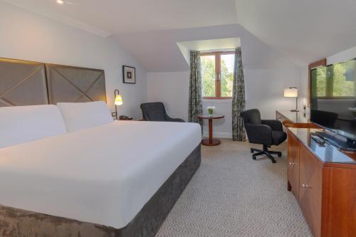 a hotel room with a large bed and a television at Glasgow Westerwood Hotel, Spa & Golf Resort in Cumbernauld