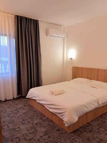 a bedroom with a large white bed with a window at Casa din Golful Dunării in Eşelniţa