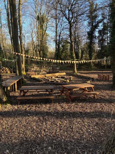 a group of picnic tables and benches in a park at Unique Suffolk Cabin with Countryside Views in Burgh