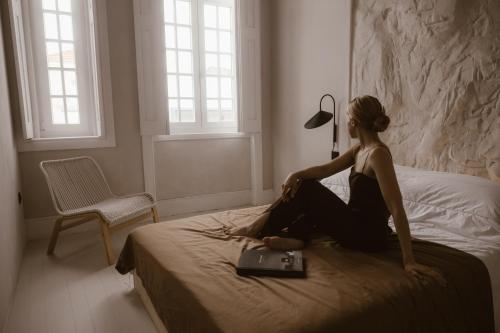 a woman sitting on a bed with a laptop at Beige Tranquil Escape by the Sea in Matosinhos