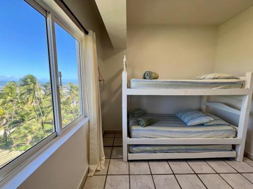 a room with a window and bunk beds with a view at Vista al Mar Residencias Laguna Blanca in Tucacas