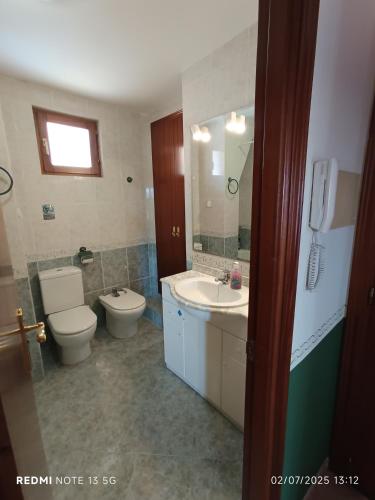 a bathroom with a toilet and a sink and a mirror at Casa Placet de Sant Joan Apto in Morella