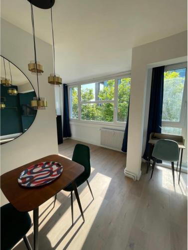 a living room with a table and chairs and windows at The Blue Jack - studio near the Casino in Le Havre