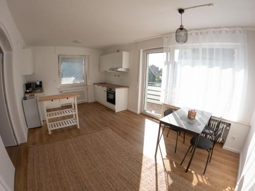 a living room with a table and a kitchen with a window at Moderne Zimmer in zentraler Lage bei Stay Time in Steinhagen