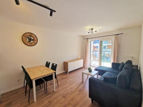 ein Wohnzimmer mit einem blauen Sofa und einem Tisch in der Unterkunft Apartamenty Złote Wydmy - Plażowa Park Międzywodzie in Międzywodzie