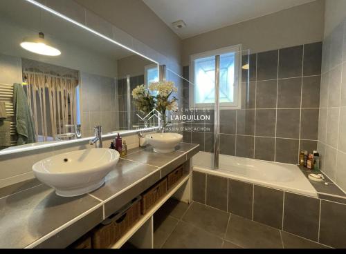 une salle de bain avec deux lavabos et une baignoire dans l'établissement Villa carioca, à Gujan-Mestras