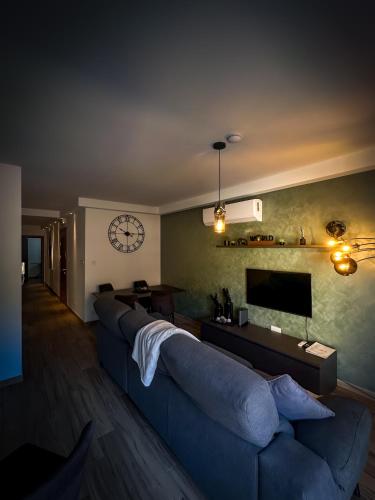 a living room with a blue couch and a clock on the wall at Camellia Luxury Apartment - 2 Bedroom in Taʼ Xbiex