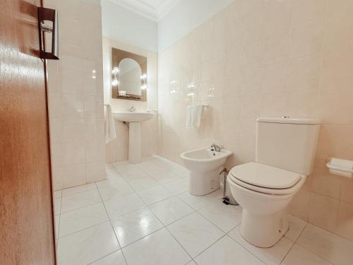 a white bathroom with a toilet and a sink at Casa do Lugar de Paços in Caldelas