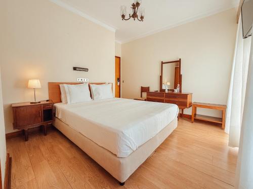 a bedroom with a large white bed and a mirror at Casa do Lugar de Paços in Caldelas