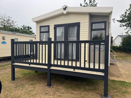 a tiny house with a black railing at Modern 6 birth caravan Hunstanton Norfolk in New Hunstanton