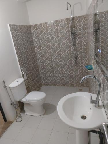 a bathroom with a toilet and a sink and a shower at Résidence Diaw's Saly in Mbour