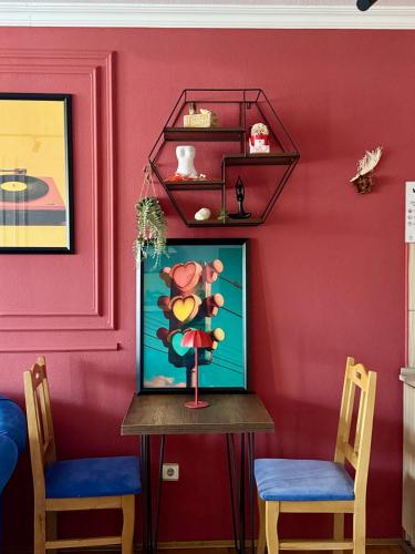 a table in a room with two chairs and a red wall at Apartment - in the center of prishtina 1 in Pristina