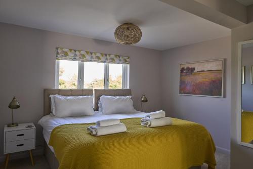 a bedroom with a yellow bed with towels on it at Harbour Lights in Southwold