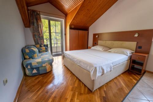 een slaapkamer met een bed en een stoel erin bij Beach Apartments Villa Holiday in Živogošće