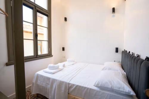 a bedroom with a bed with white sheets and a window at Özel Otel in Ayvalık