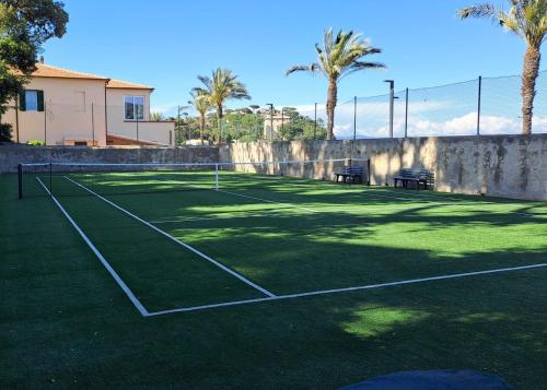 Una cancha de tenis con dos bancos y palmeras. en Castello Bellariva, en Cavo