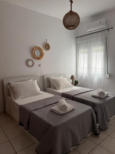 two beds in a white room with towels on them at Anemõessa in Korinthos