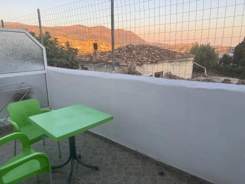a green table and a green chair on a balcony at Petros rooms in Himare