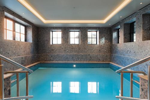 a swimming pool in a building with windows at Van der Valk TheaterHotel De Oranjerie in Roermond