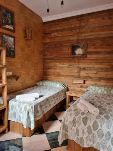 two beds in a room with wooden walls at Molino Romano in Alcalá del Valle