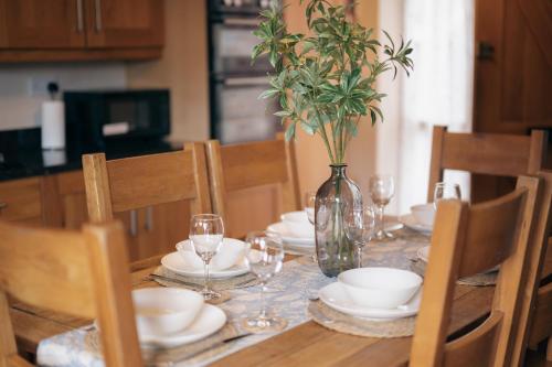 a table with plates and glasses and a vase with a plant at The Old Mill at Barnacre - Cosy cottage with private hot tub & pool access in Wirral