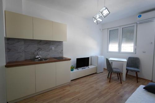 a kitchen with white cabinets and a desk with a television at Le Nina Apartments - Deluxe and Studio in Strumica