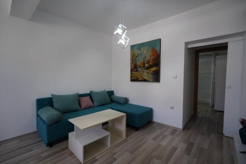 a living room with a blue couch and a table at Le Nina Apartments - Deluxe and Studio in Strumica