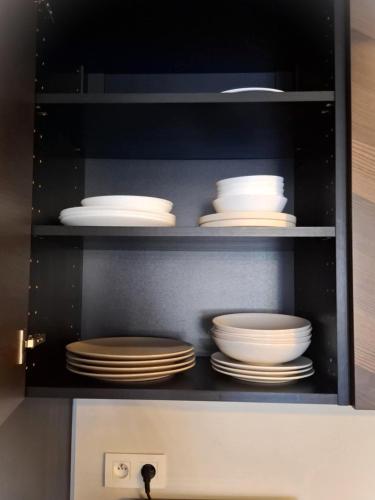 a cabinet filled with white plates and dishes at ORBIS Premium apartment in Nitra