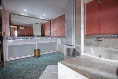 a bathroom with a tub and a large mirror at Zalagh Parc Palace in Fès