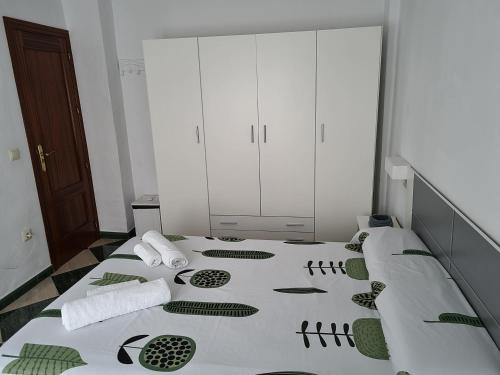 a bedroom with a large white bed with green patterns on it at Molino Romano in Alcalá del Valle