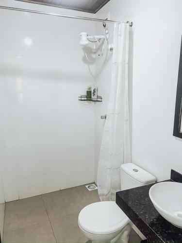 a white bathroom with a toilet and a sink at Casa Pasárgada in Palmas