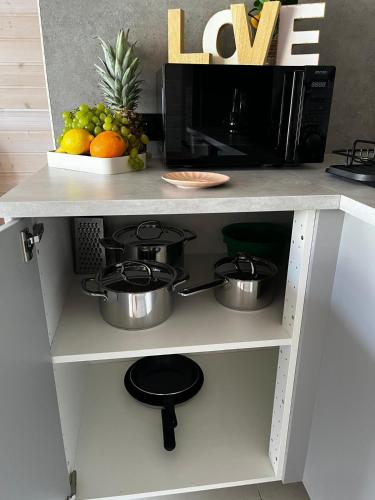 a kitchen shelf with pots and pans and a microwave at Aster domki Sarbinowo in Sarbinowo