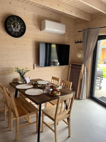a dining room table with chairs and a clock on the wall at Aster domki Sarbinowo in Sarbinowo