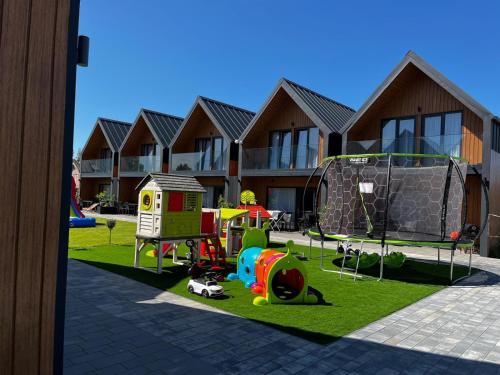a playground with play equipment in front of a building at Aster domki Sarbinowo in Sarbinowo