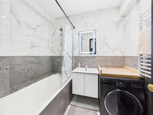 a bathroom with a washing machine and a tub at Panoramique du Bois de Vincennes à Paris, avec balcon terrasse in Saint-Maurice